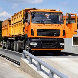 orange truck with grain is weighed on the scales in the grain storage area. Truck scales