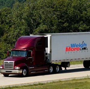 Truck on freeway with weigh-more weighbridge seller branding